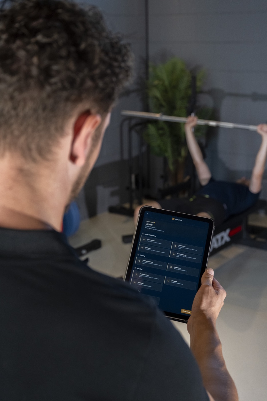 Trainer bekijkt het Kinetiq-portaal op een tablet terwijl een klant traint